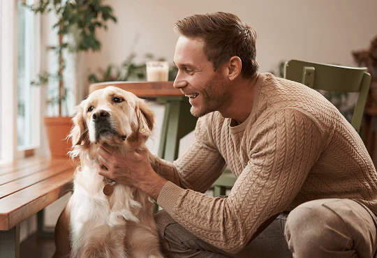 Smiling man petting his golden retriever